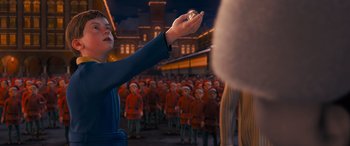 Movie still from “The Polar Express” (2004), directed by Robert Zemeckis – An image of a person holding a ball in front of a crowd of people; Medium shot, High angle