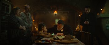 Movie still from “The Pope's Exorcist” (2023), directed by Julius Avery – A man and a little girl sitting at a dinner table; Medium shot, Over the shoulder angle
