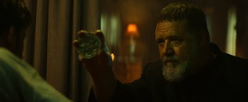 Movie still from “The Pope's Exorcist” (2023), directed by Julius Avery – An older man holding a glass in his hand; Close Up shot, Over the shoulder angle