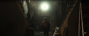 Movie still from “The Pope's Exorcist” (2023), directed by Julius Avery – A man is walking through a dark room; Wide shot, Low angle