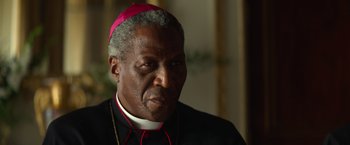 Movie still from “The Pope's Exorcist” (2023), directed by Julius Avery – A person wearing a priest's outfit; Close Up shot, Over the shoulder angle