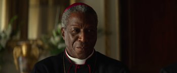 Movie still from “The Pope's Exorcist” (2023), directed by Julius Avery – A person wearing a priest's outfit; Close Up shot, Over the shoulder angle