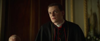 Movie still from “The Pope's Exorcist” (2023), directed by Julius Avery – A man wearing a black robe and a red and white collar; Close Up shot, Low angle