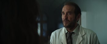 Movie still from “The Pope's Exorcist” (2023), directed by Julius Avery – A person wearing a suit and tie; Close Up shot, Over the shoulder angle