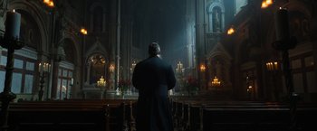 Movie still from “The Pope's Exorcist” (2023), directed by Julius Avery – A man standing in front of candles in a church; Wide shot, Low angle