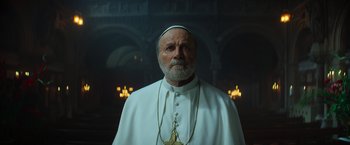 Movie still from “The Pope's Exorcist” (2023), directed by Julius Avery – An older man wearing a white robe and a white hat; Close Up shot, Low angle