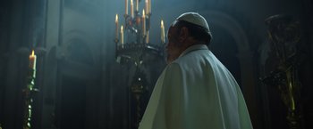 Movie still from “The Pope's Exorcist” (2023), directed by Julius Avery – A man wearing a white robe and a white hat; Medium shot, Low angle