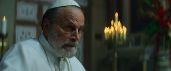 Movie still from “The Pope's Exorcist” (2023), directed by Julius Avery – An old man with a beard wearing a white hat; Close Up shot, Low angle