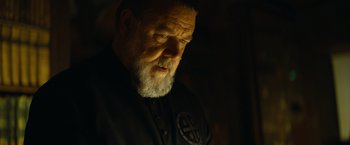 Movie still from “The Pope's Exorcist” (2023), directed by Julius Avery – An old man with a beard and a black shirt; Close Up shot, Low angle
