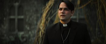 Movie still from “The Pope's Exorcist” (2023), directed by Julius Avery – A man in a priest's outfit looking at the camera; Close Up shot, Low angle