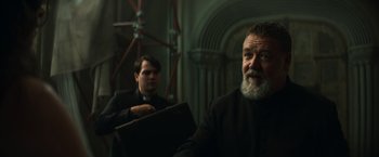 Movie still from “The Pope's Exorcist” (2023), directed by Julius Avery – A man with a beard is standing next to another man; Medium shot, Low angle