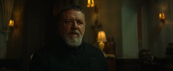 Movie still from “The Pope's Exorcist” (2023), directed by Julius Avery – A man with a gray beard wearing a black shirt; Close Up shot, Low angle