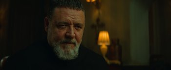 Movie still from “The Pope's Exorcist” (2023), directed by Julius Avery – An older man with a beard is looking at the camera; Close Up shot, Over the shoulder angle