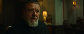 Movie still from “The Pope's Exorcist” (2023), directed by Julius Avery – An older man with a beard is sitting in a room; Close Up shot, Over the shoulder angle