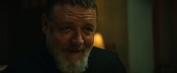 Movie still from “The Pope's Exorcist” (2023), directed by Julius Avery – An older man with a beard smiling for the camera; Close Up shot, Over the shoulder angle