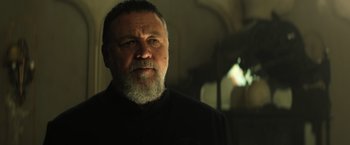 Movie still from “The Pope's Exorcist” (2023), directed by Julius Avery – An older man with a beard is looking at the camera; Close Up shot, Low angle