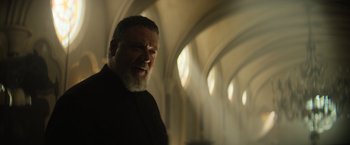 Movie still from “The Pope's Exorcist” (2023), directed by Julius Avery – An older man with a beard is looking at the camera; Medium shot, Low angle