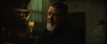 Movie still from “The Pope's Exorcist” (2023), directed by Julius Avery – An older man with a beard is sitting in a chair; Close Up shot, Low angle