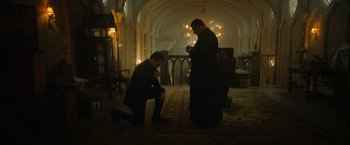 Movie still from “The Pope's Exorcist” (2023), directed by Julius Avery – A man kneeling down in front of a priest; Wide shot, Low angle