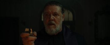 Movie still from “The Pope's Exorcist” (2023), directed by Julius Avery – An older man with a beard and a cigarette in his mouth; Close Up shot, Low angle