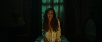 Movie still from “The Pope's Exorcist” (2023), directed by Julius Avery – A woman sitting on top of a bed in front of a window; Medium shot, Low angle