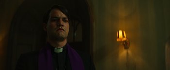Movie still from “The Pope's Exorcist” (2023), directed by Julius Avery – A man wearing a priest's outfit and a purple stole; Close Up shot, Low angle