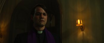 Movie still from “The Pope's Exorcist” (2023), directed by Julius Avery – A man wearing a priest's outfit and a purple stole; Close Up shot, Low angle