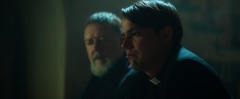 Movie still from “The Pope's Exorcist” (2023), directed by Julius Avery – Two men are sitting in a dark room; Close Up shot, Over the shoulder angle