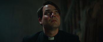 Movie still from “The Pope's Exorcist” (2023), directed by Julius Avery – A man wearing a priest's outfit looking upward; Close Up shot, Low angle