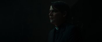 Movie still from “The Pope's Exorcist” (2023), directed by Julius Avery – A man wearing a priest's outfit is looking up; Close Up shot, Low angle