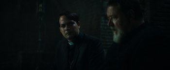 Movie still from “The Pope's Exorcist” (2023), directed by Julius Avery – A priest and a man in a dark room; Close Up shot, Over the shoulder angle
