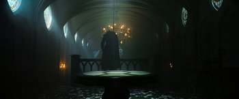 Movie still from “The Pope's Exorcist” (2023), directed by Julius Avery – A man in a black coat standing in a dark room; Wide shot, Low angle