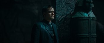 Movie still from “The Pope's Exorcist” (2023), directed by Julius Avery – A man wearing a suit and tie standing in a dark room; Close Up shot, High angle