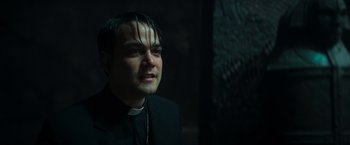 Movie still from “The Pope's Exorcist” (2023), directed by Julius Avery – A man in a priest's outfit looking into the camera; Close Up shot, High angle