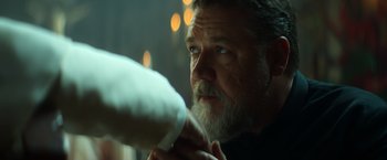 Movie still from “The Pope's Exorcist” (2023), directed by Julius Avery – A man with a beard is holding a blow dryer; Close Up shot, Over the shoulder angle