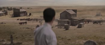 Movie still from “The Power of the Dog” (2021), directed by Jane Campion – A man standing in front of an old western town; Extreme Wide shot, Over the shoulder angle