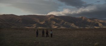 Movie still from “The Power of the Dog” (2021), directed by Jane Campion – A group of people standing on top of a grass covered field; Extreme Wide shot, Low angle