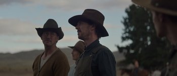 Movie still from “The Power of the Dog” (2021), directed by Jane Campion – A man wearing a hat standing next to another man wearing a hat; Medium shot, Over the shoulder angle