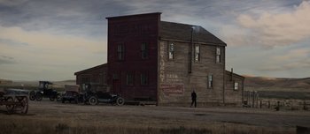 Movie still from “The Power of the Dog” (2021), directed by Jane Campion – A man walking in front of an old building; Extreme Wide shot, Low angle