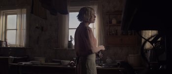 Movie still from “The Power of the Dog” (2021), directed by Jane Campion – A woman standing in a kitchen holding a knife; Medium shot, Over the shoulder angle