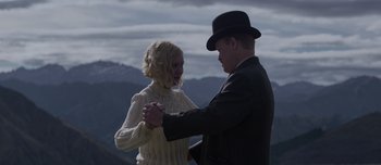 Movie still from “The Power of the Dog” (2021), directed by Jane Campion – A man and a woman holding hands in front of a mountain range; Medium shot, Low angle