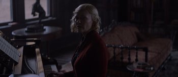 Movie still from “The Power of the Dog” (2021), directed by Jane Campion – A woman in a red jacket is playing a piano; Medium shot, Over the shoulder angle