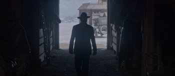Movie still from “The Power of the Dog” (2021), directed by Jane Campion – A man wearing a hat walking through a barn; Wide shot, Over the shoulder angle