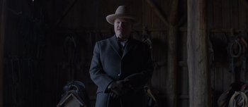 Movie still from “The Power of the Dog” (2021), directed by Jane Campion – A man in a suit and a hat standing in a barn; Medium shot, Low angle