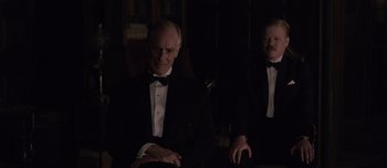 Movie still from “The Power of the Dog” (2021), directed by Jane Campion – A man in a black tuxedo sitting next to another man in a black tuxedo; Medium shot, Over the shoulder angle