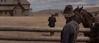 Movie still from “The Power of the Dog” (2021), directed by Jane Campion – A man in a cowboy hat walking across a dirt field; Wide shot, Over the shoulder angle