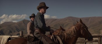 Movie still from “The Power of the Dog” (2021), directed by Jane Campion – Two men on horses in the mountains with mountains in the background; Medium shot, Low angle