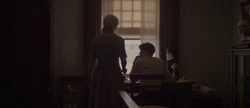 Movie still from “The Power of the Dog” (2021), directed by Jane Campion – Two people sitting at a table in front of a window; Medium shot, Over the shoulder angle