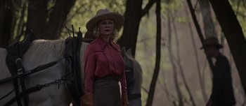 Movie still from “The Power of the Dog” (2021), directed by Jane Campion – A woman wearing a cowboy hat standing next to a horse; Medium shot, Over the shoulder angle