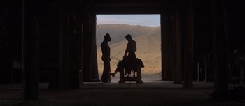 Movie still from “The Power of the Dog” (2021), directed by Jane Campion – Two men standing in front of an open door; Wide shot, Low angle